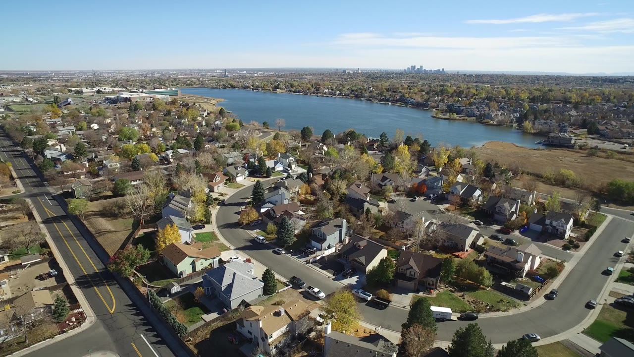 Wide aerial of a lakeside subdivision with homes and streets.