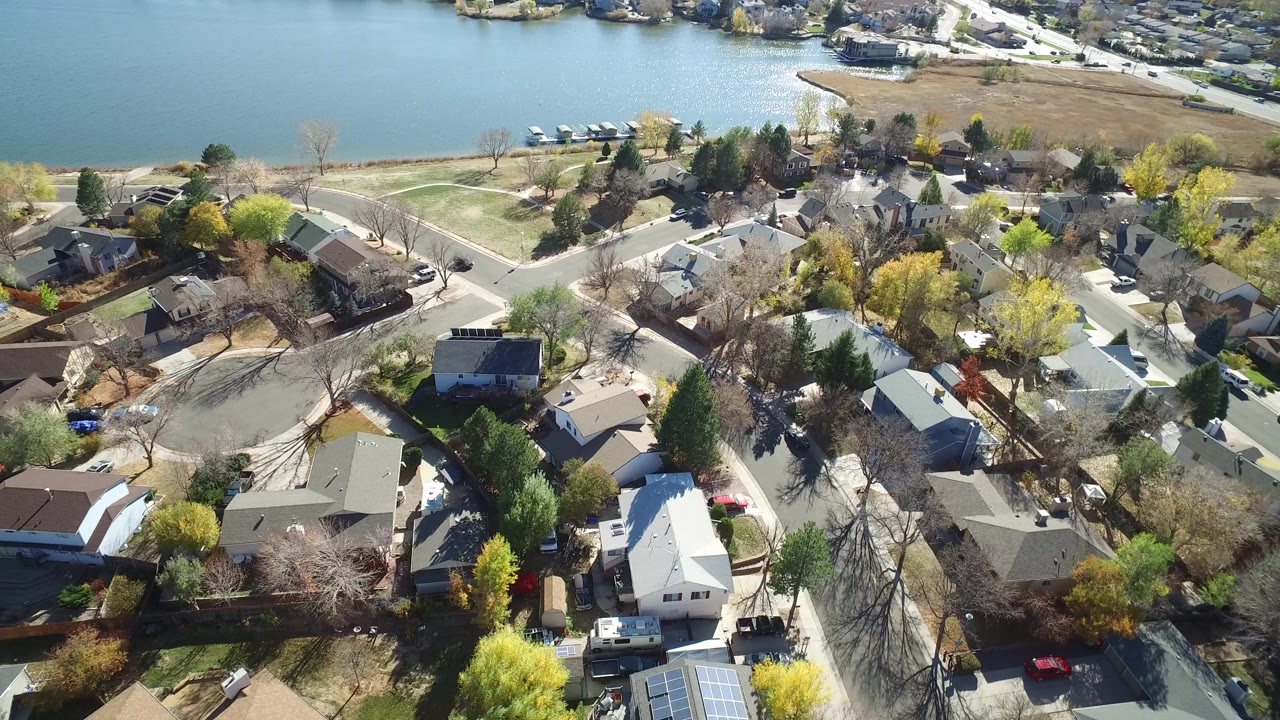 Aerial view of houses, streets, trees, and water beyond the neighborhood.