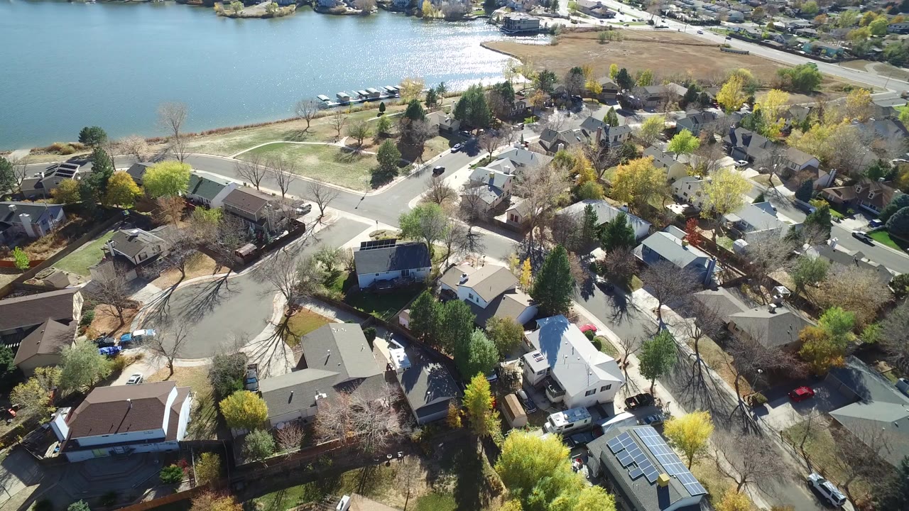 Aerial view of lakeside homes, streets, trees, and shoreline.