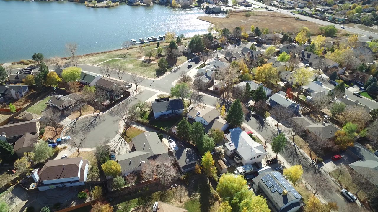 Drone-style view of rooftops, roads, trees, and lake water.