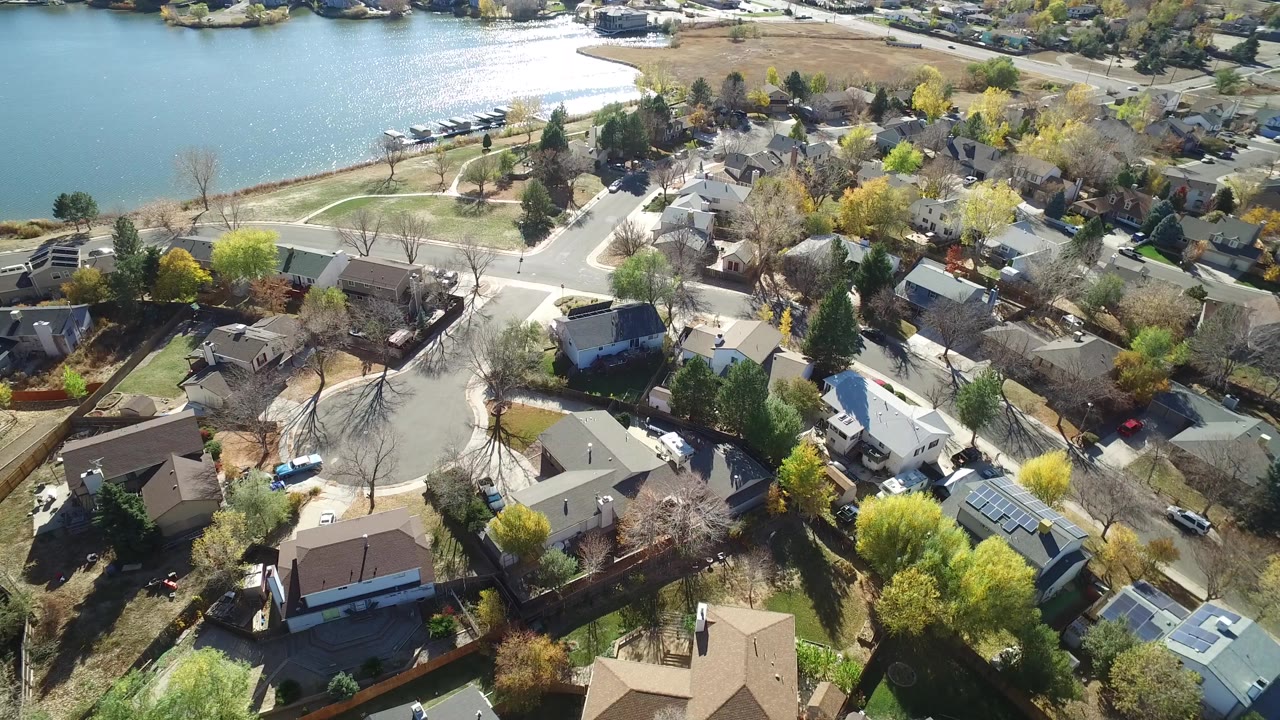 Aerial view of houses and curving streets beside a lake
