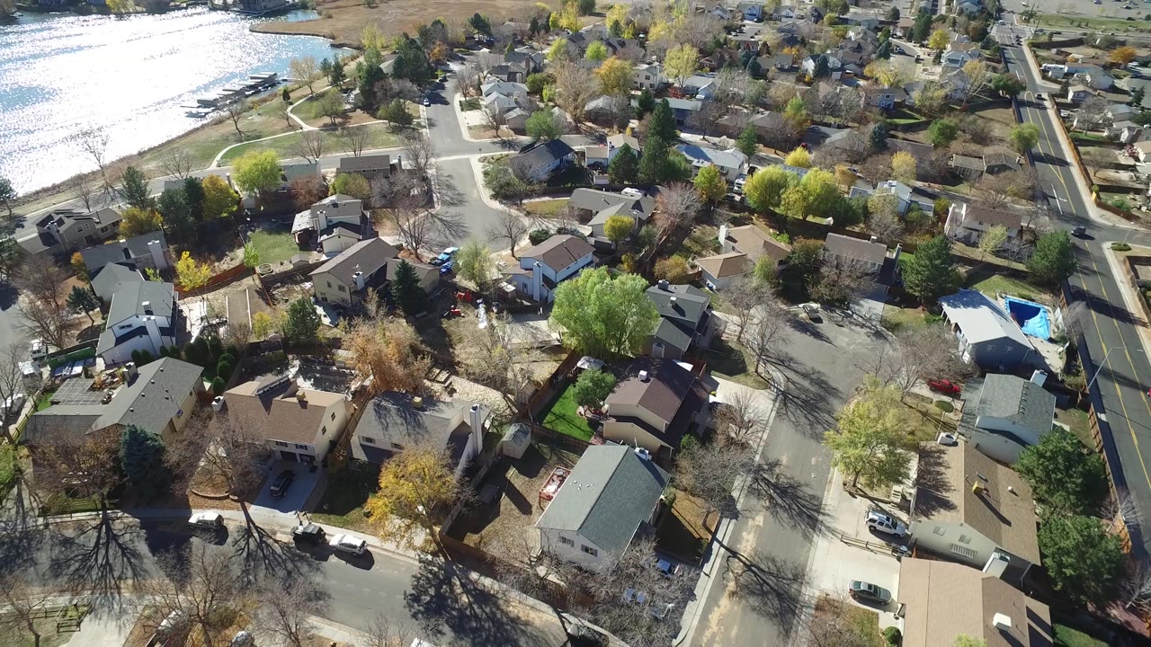 Suburban streets and homes seen from above near a reflective lake.