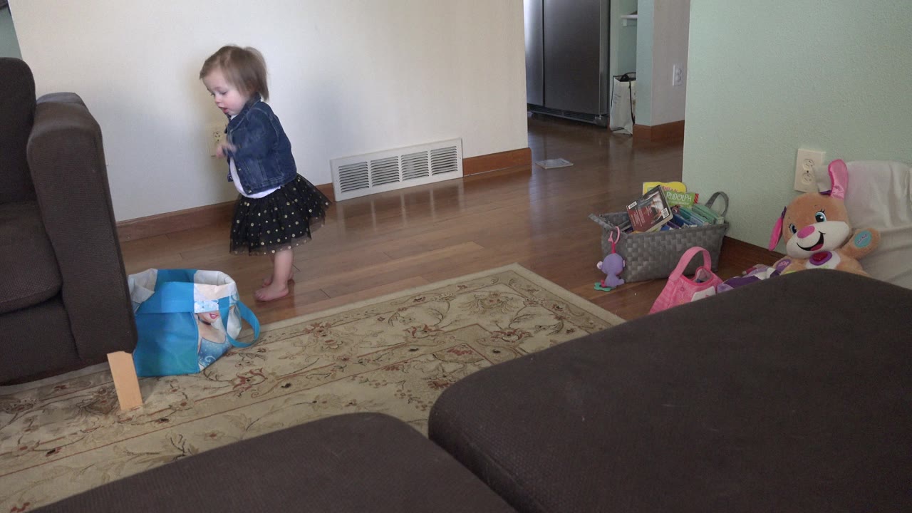 Young girl standing near a wall in a living room.