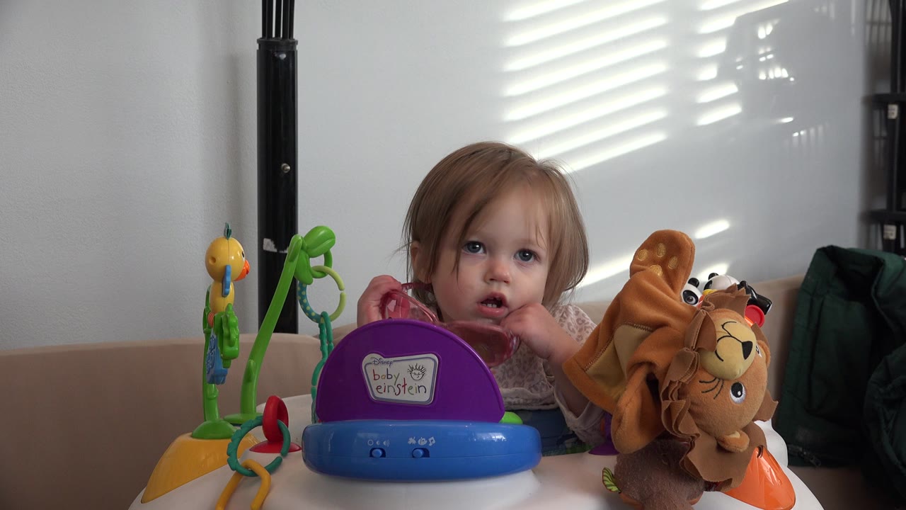 Young child seated behind colorful toys at a white table.