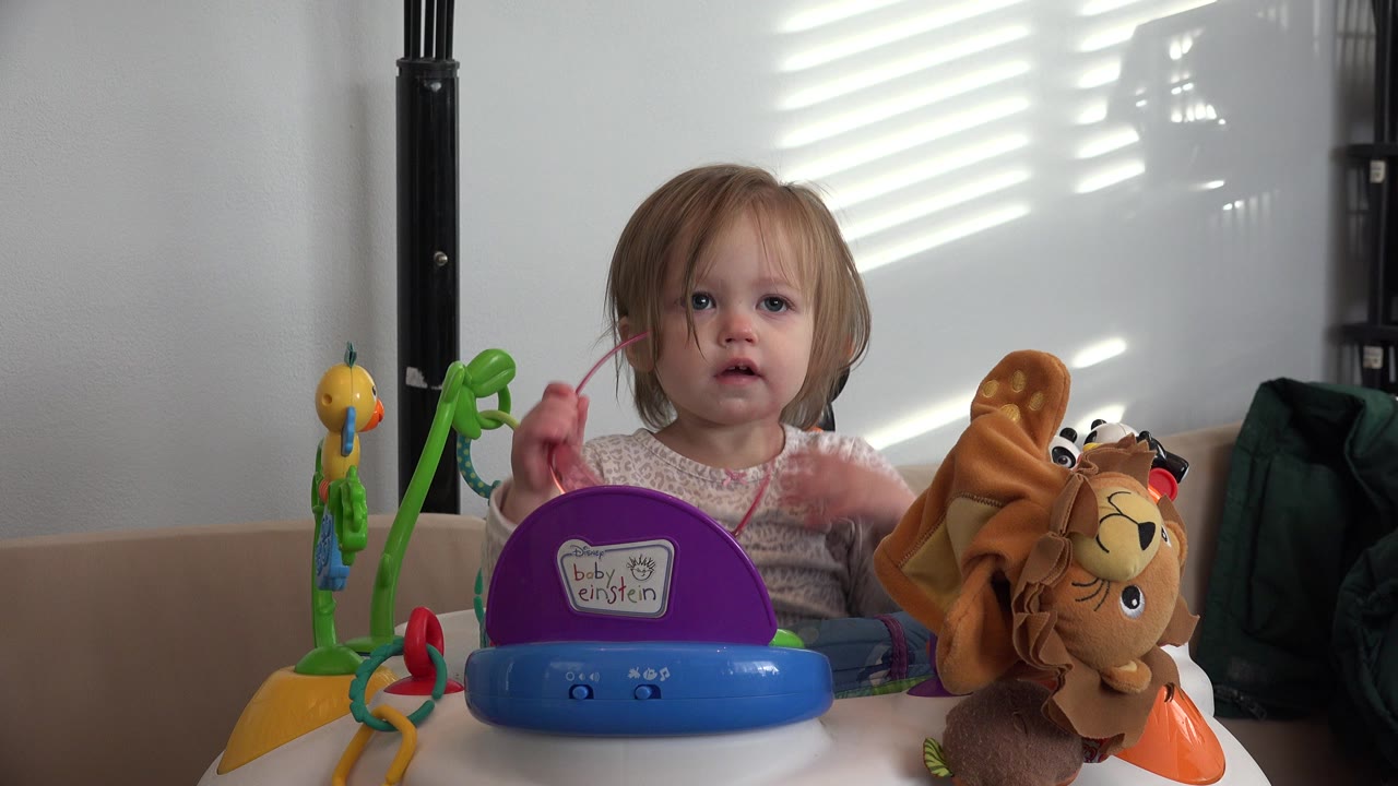 Toddler at a table with colorful toys and a plush lion.