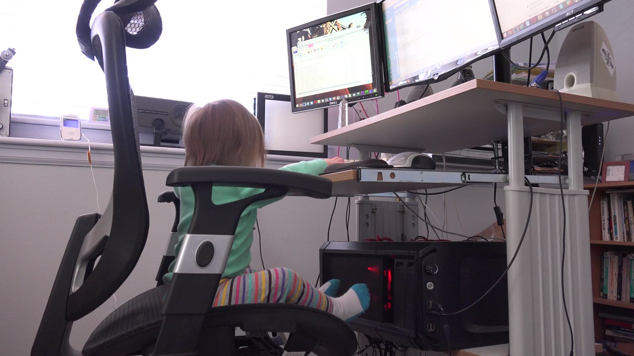 At 0:00, a child in a green shirt sits with their back to camera in a black office chair at a computer desk in Westminster, Colorado.