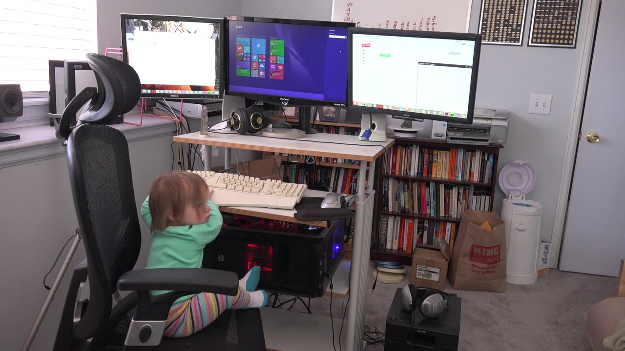At 0:01, the child leans forward toward the large keyboard while three desktop monitors glow above the desk in the Westminster home office scene.