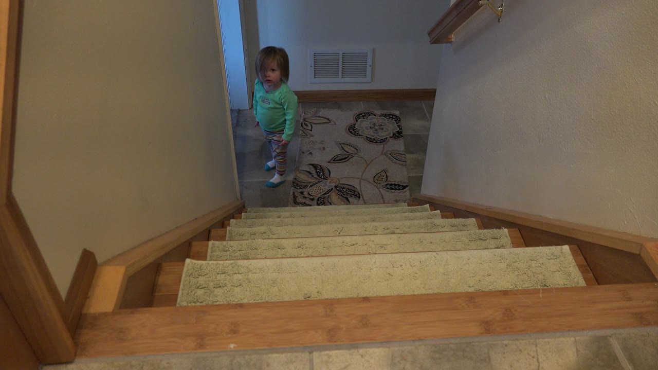 Young girl standing at the bottom of an indoor staircase.