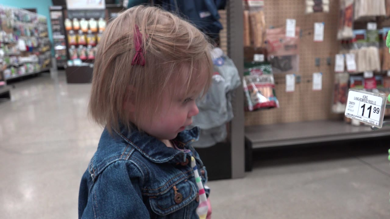 Young child in a denim jacket standing in a store aisle.