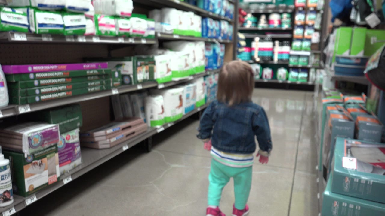 Toddler walking away down a hygiene aisle.