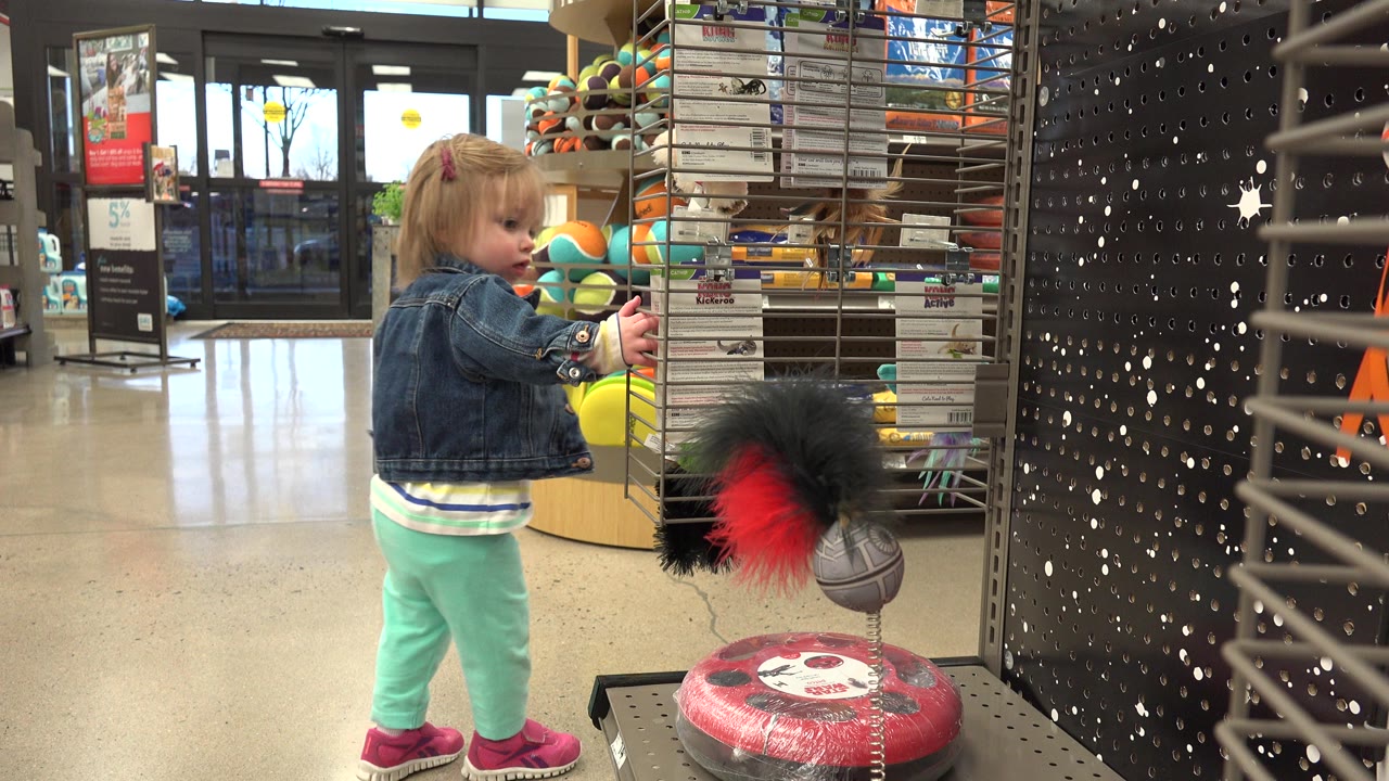 Young child standing beside a toy display in a store.