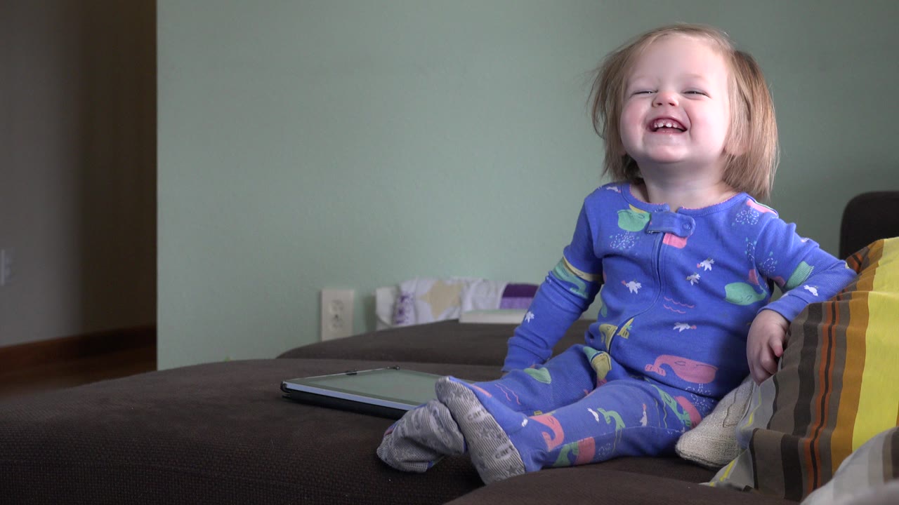 Laughing blonde toddler seated on a couch
