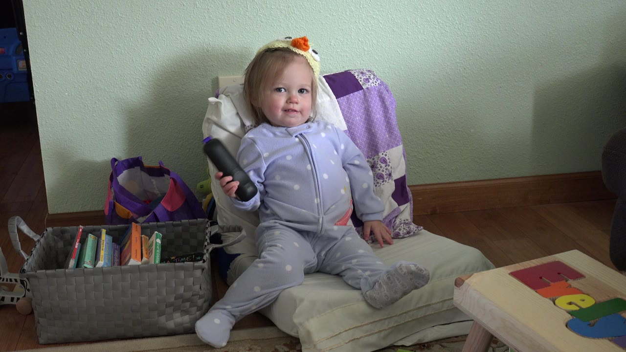 Baby sitting in an armchair holding a remote control.