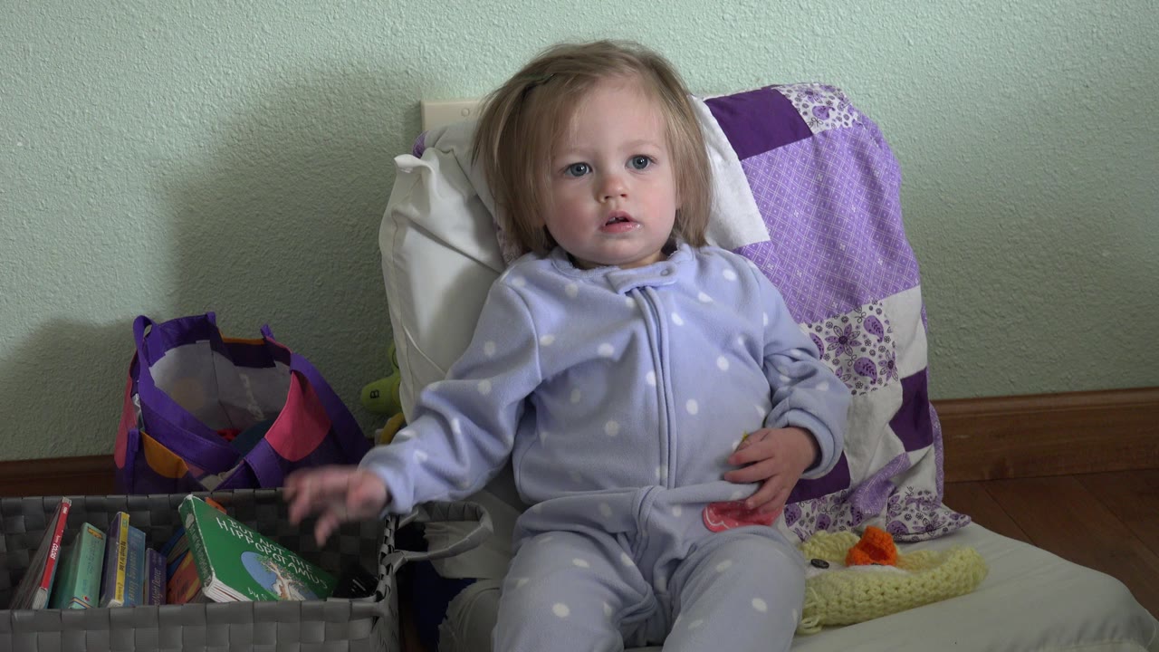 In Westminster, Colorado, the toddler remains seated and looks forward while the left hand rests near the basket of books at the side of the chair.