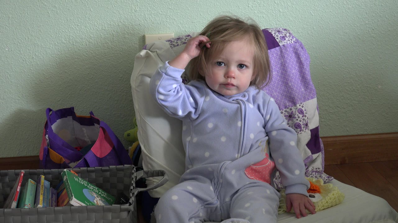 At 0:01 in Westminster, Colorado, the child faces the camera with her right hand in her hair and her other hand resting near her lap.
