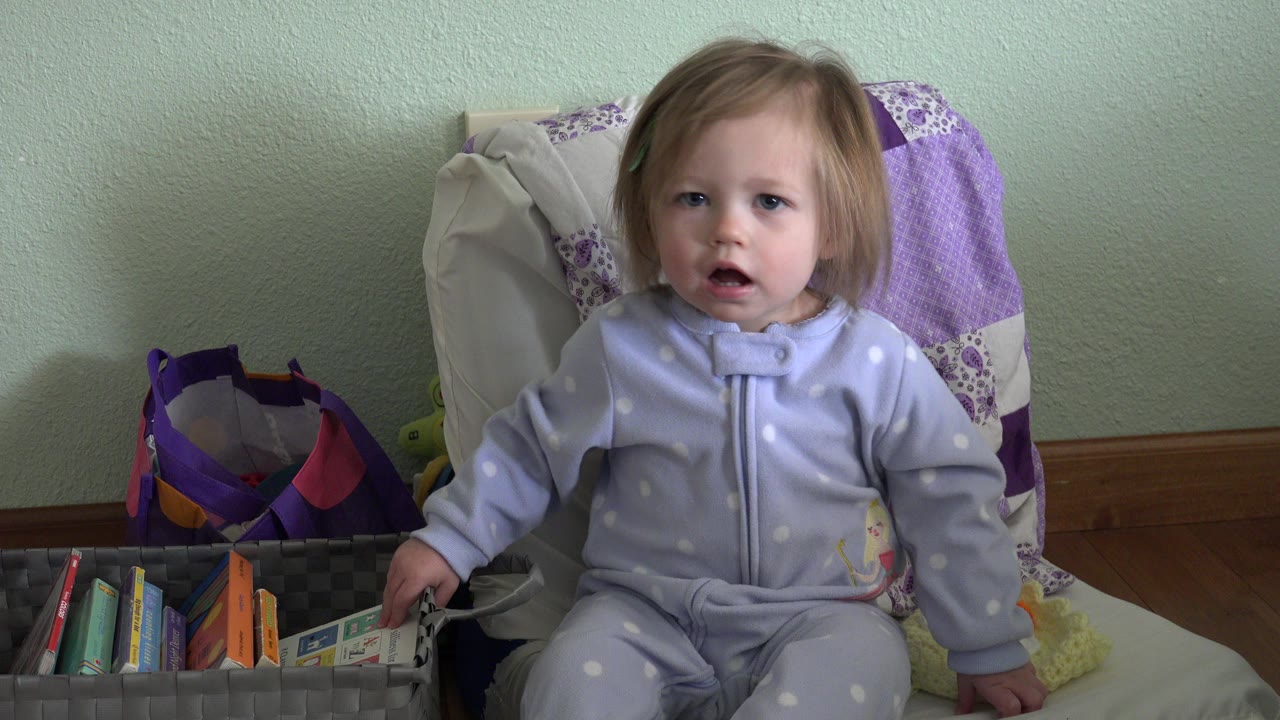 Toddler seated beside a basket of books.