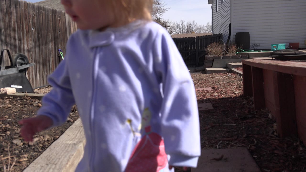Child in purple top close to a backyard camera.