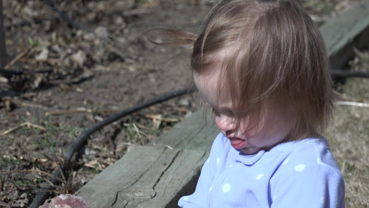 The child remains near the ledge in Westminster, Colorado, looking down while strands of blonde hair blow across the forehead and cheek.