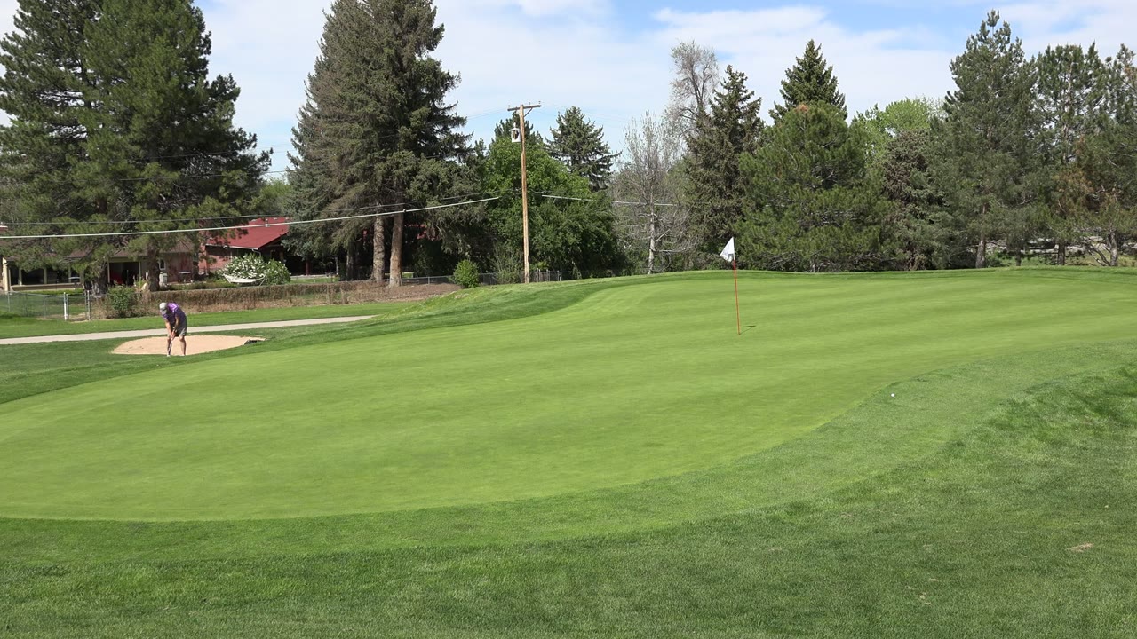 Wide golf course fairway with sand bunker and distant golfer.