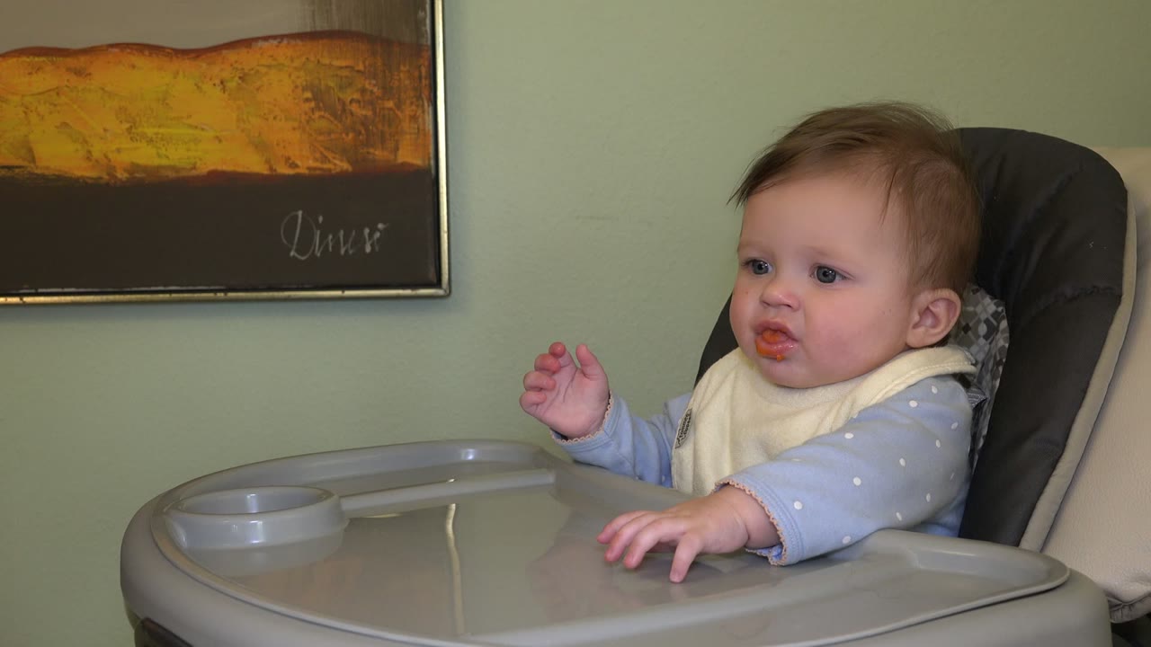 Baby in a high chair with food on their mouth