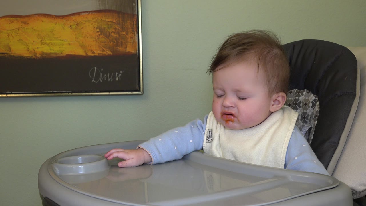 Baby in a high chair with food around the mouth.
