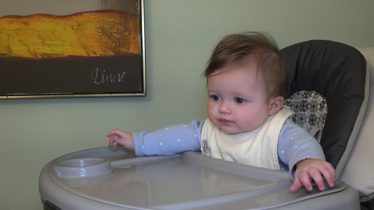 Baby seated in a high chair beside a tray.