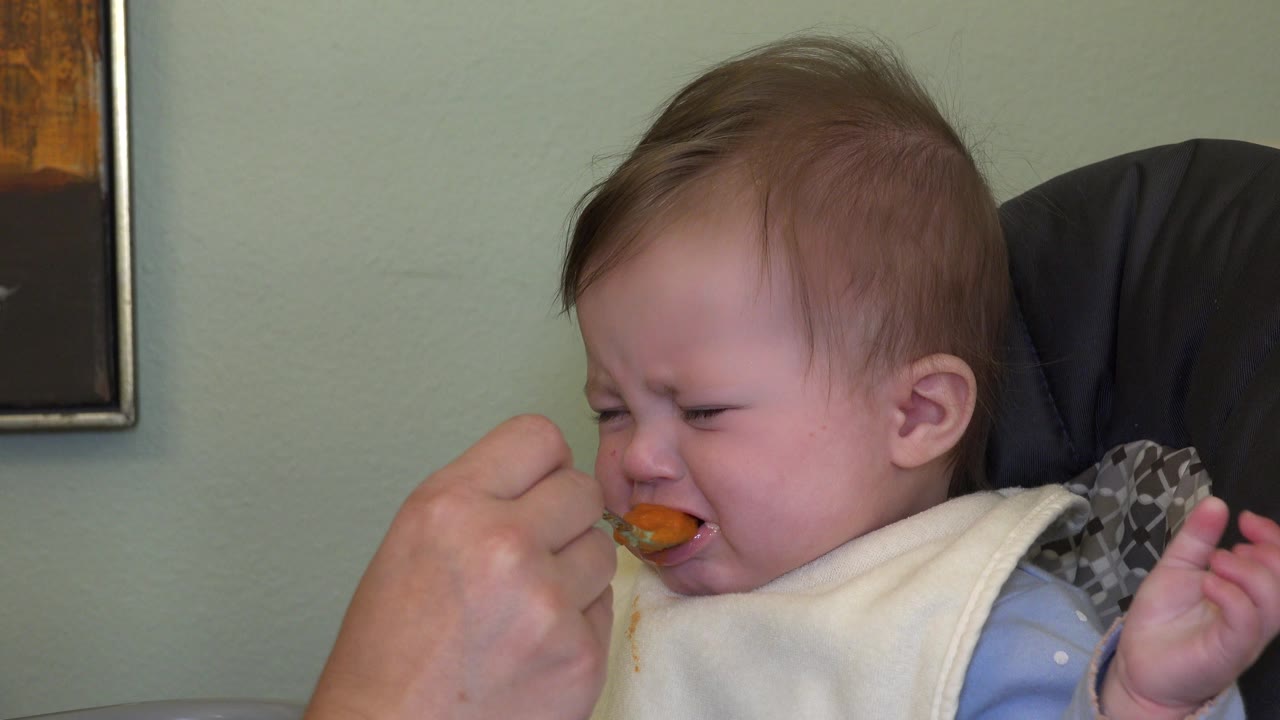 In Westminster, Colorado, the spoon remains at the baby's mouth as the child squeezes their eyes shut in the high chair.