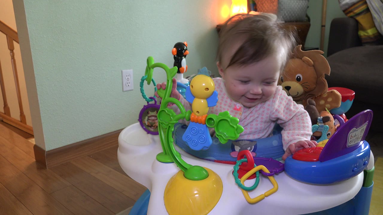 The toddler looks downward toward the tray toys while seated in the activity chair inside the Westminster, Colorado home.
