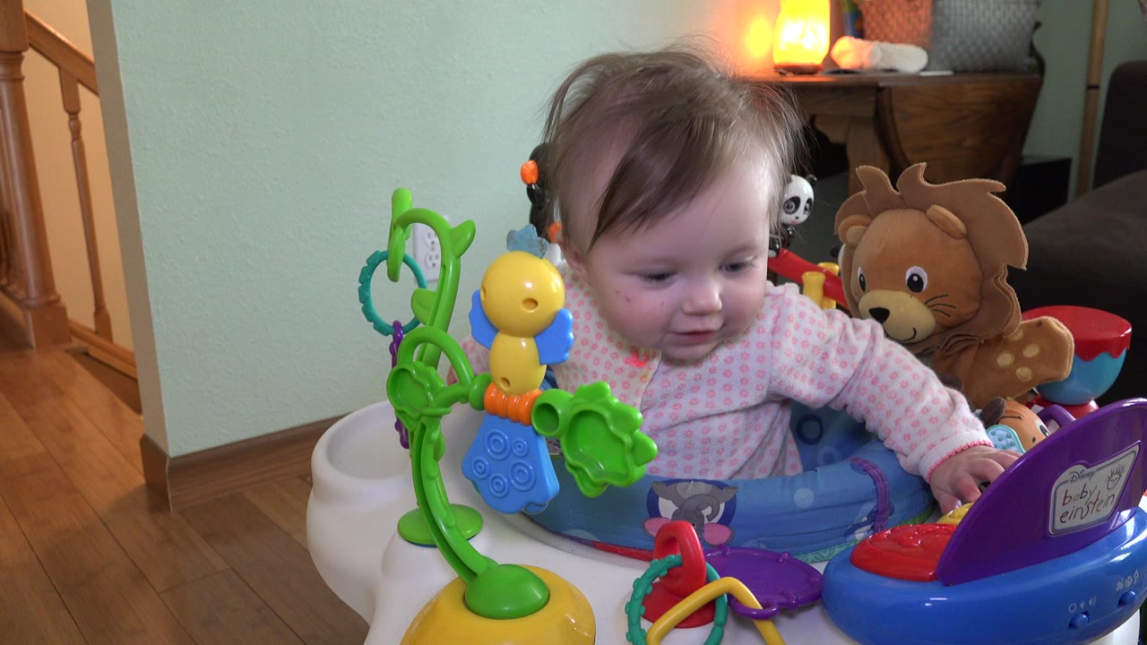 Baby seated in a toy activity chair in a home interior.