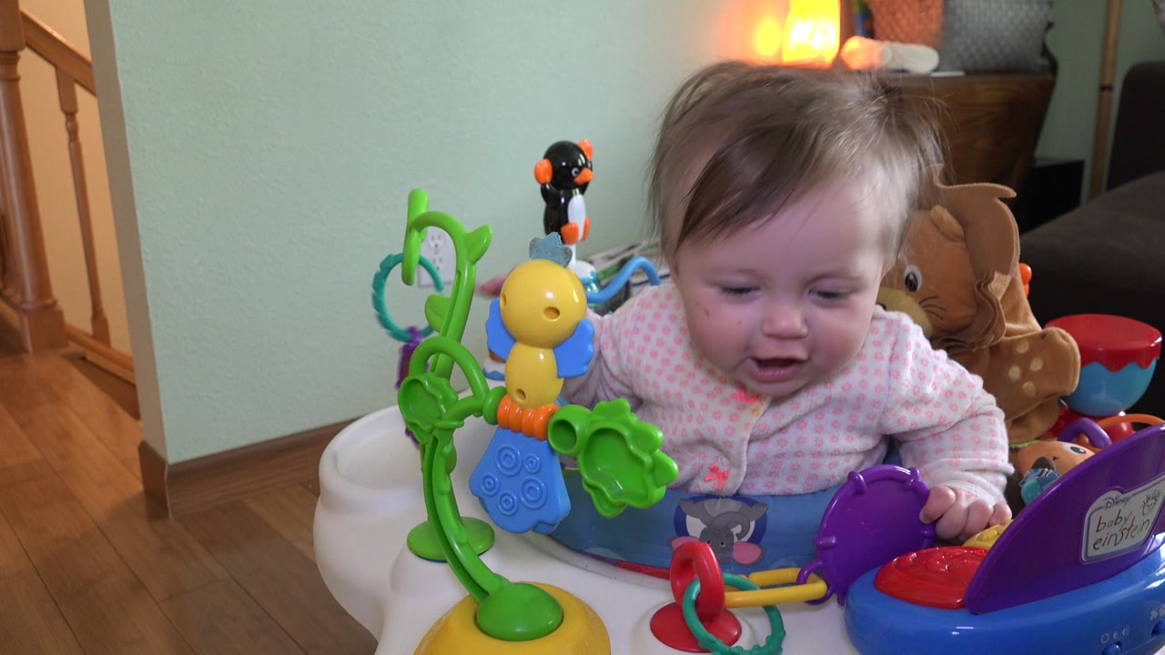 Baby seated among colorful toys in a home interior.