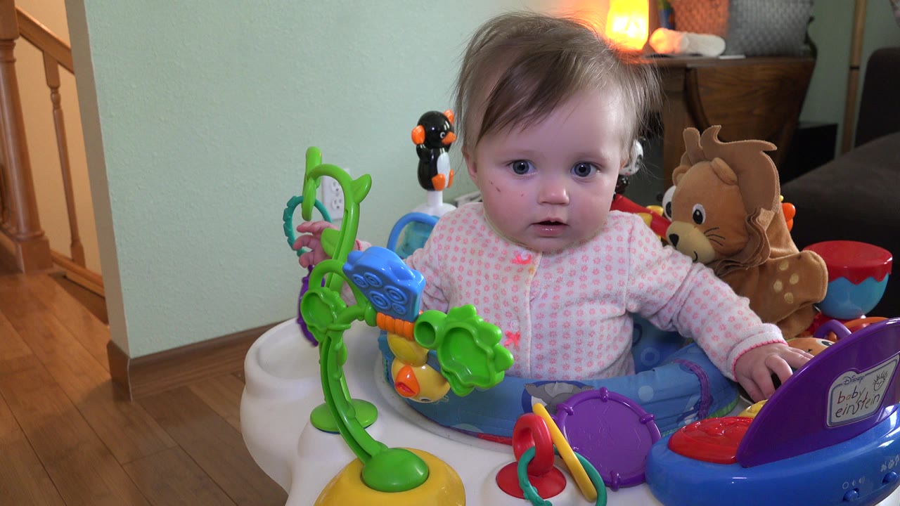 Baby in activity chair surrounded by colorful toys
