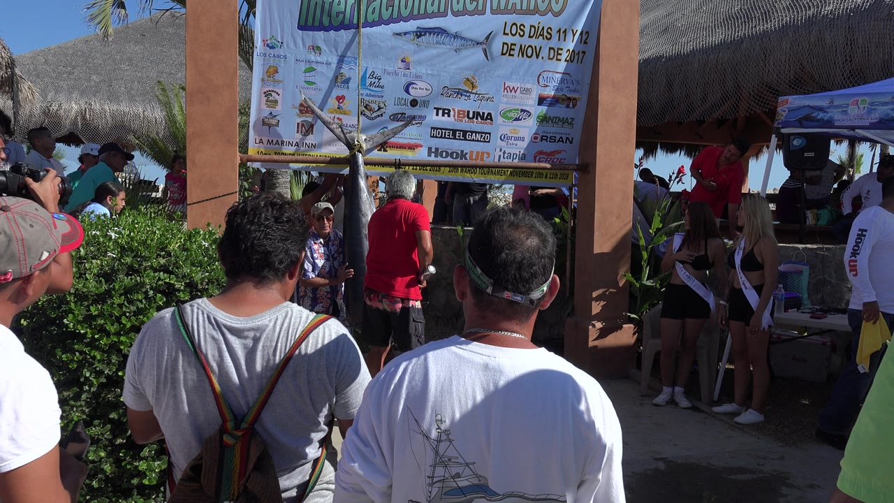 Tourists standing below a large resort event sign.