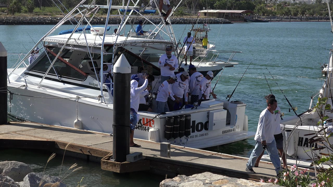 People gathered beside a white fishing boat at a dock
