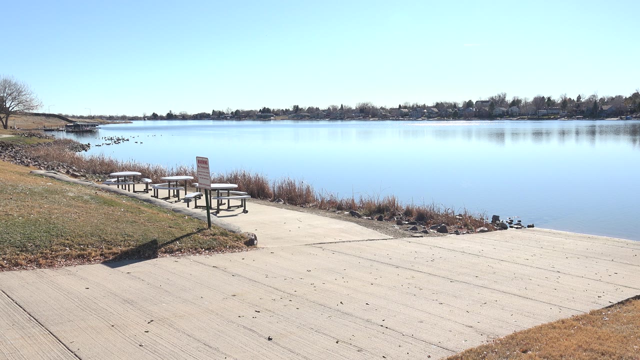 Concrete lakeside ramp beside picnic tables and calm water