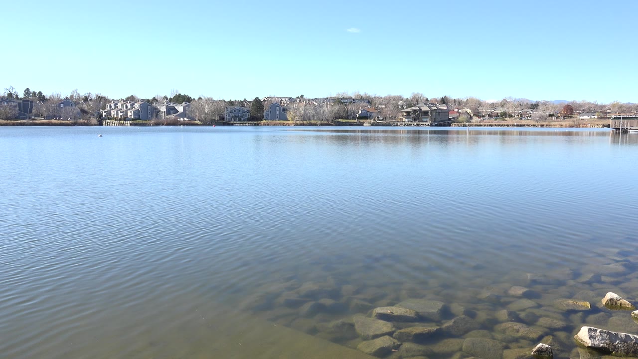 Wide lake view with shallow rocks and distant houses