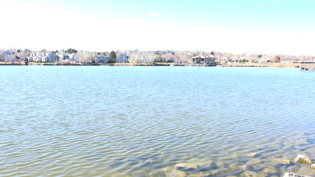 Early frame from Hidden Lake, Colorado, with the rippled lake surface filling most of the view and a thin band of houses and trees along the far shore.