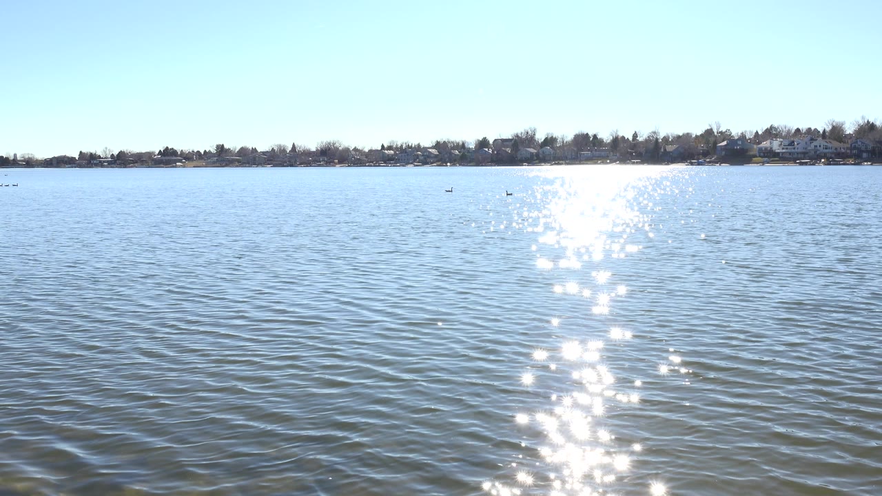 Lake horizon with bright reflected sunlight on choppy ripples.