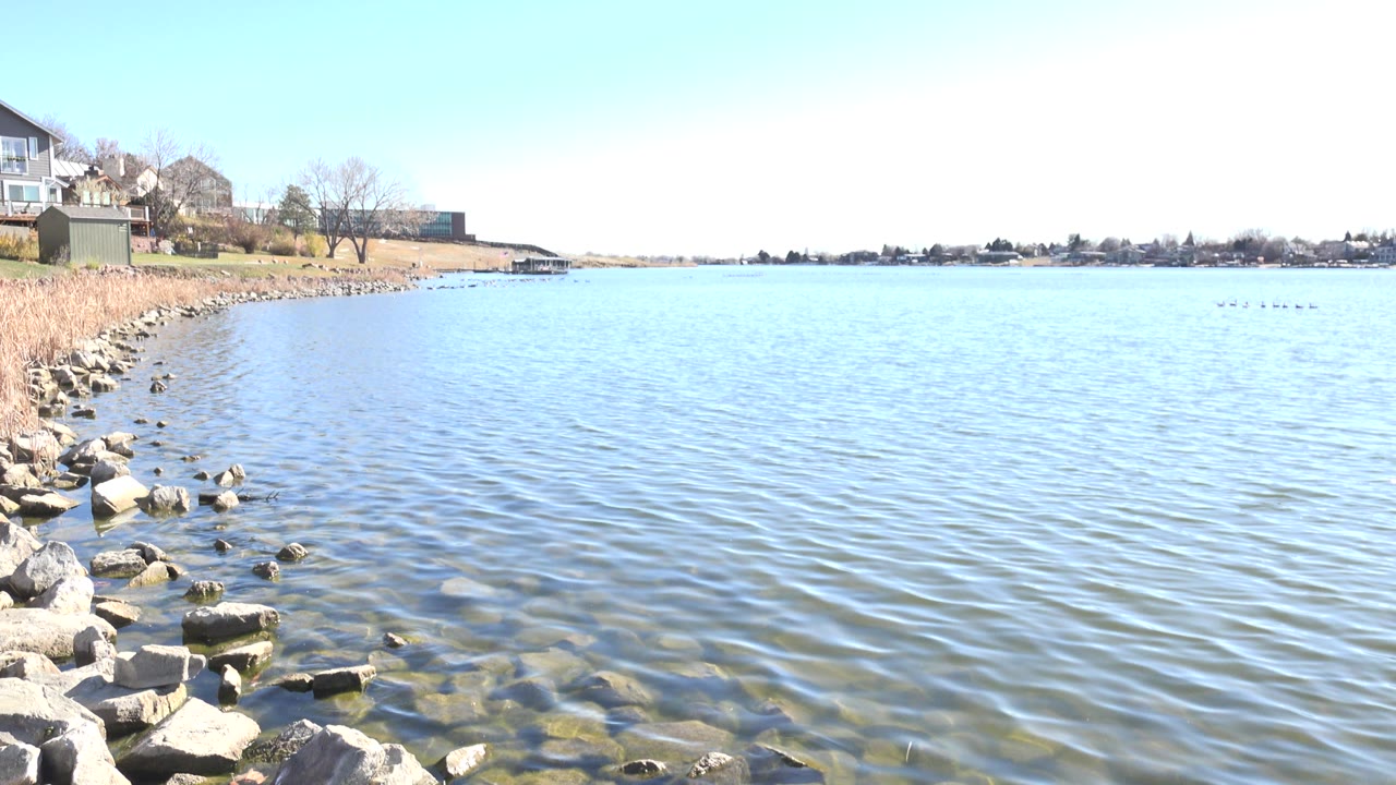Rocky shoreline beside rippled lake water under bright sky