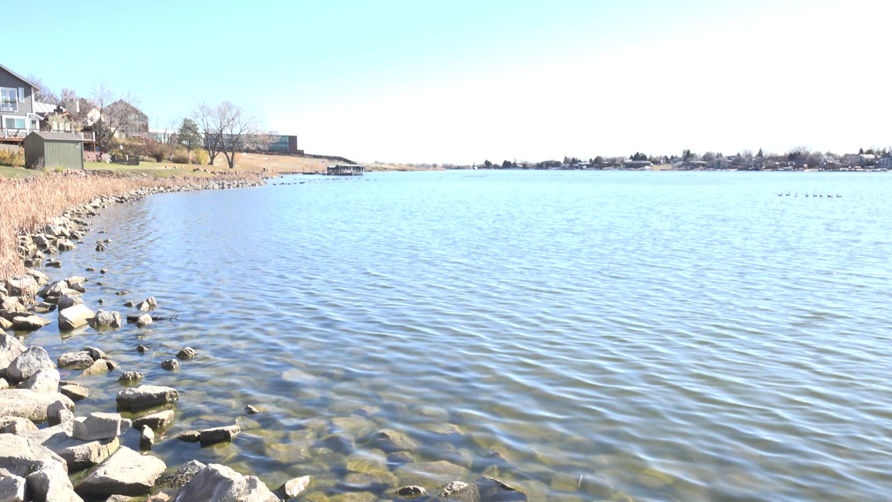At Hidden Lake Colorado, the left shoreline rocks remain prominent while small surface ripples spread across the lake and no visible people appear.