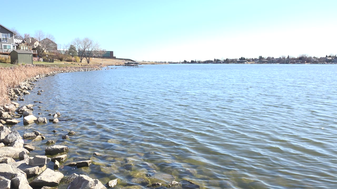 Rocky lakeshore with rippling water and houses along the left bank.