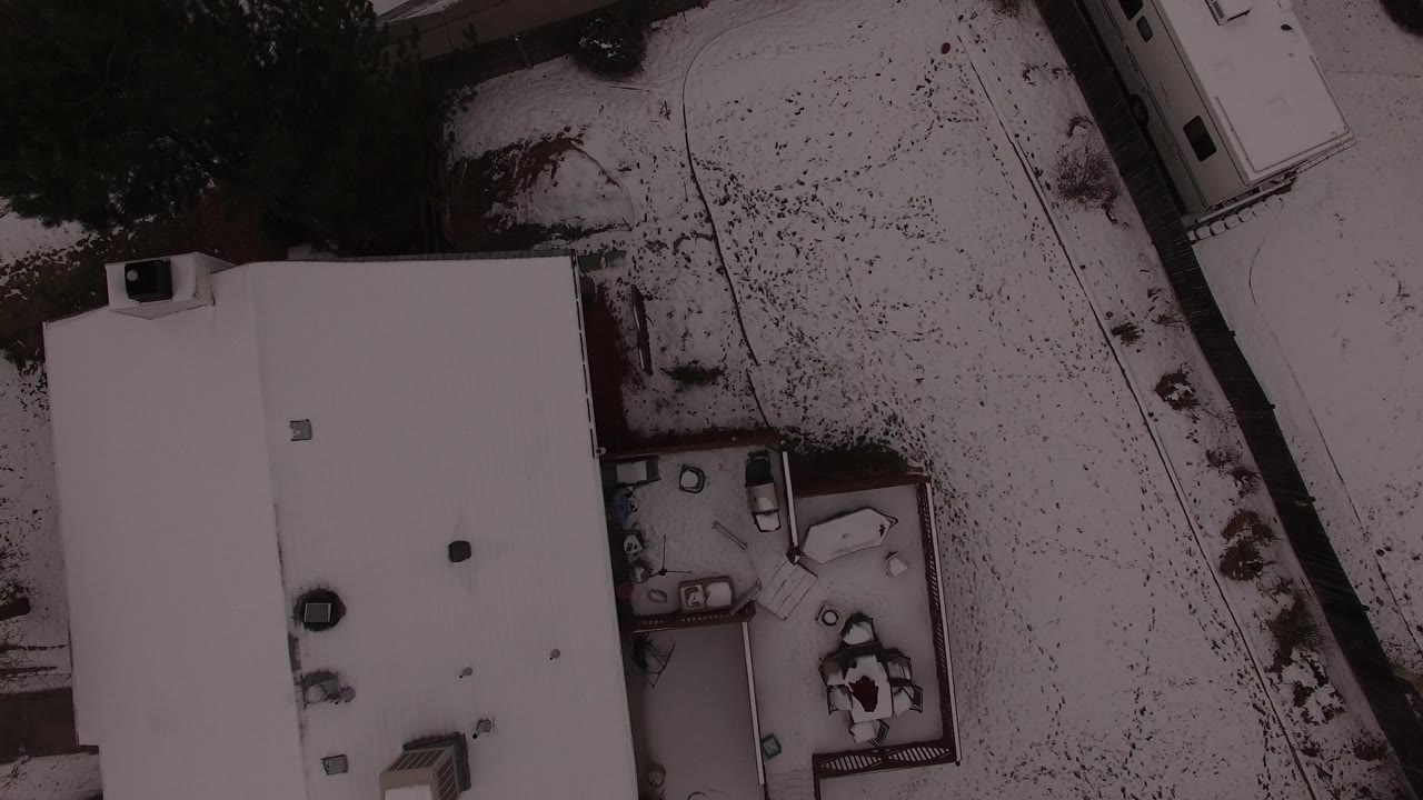 Top-down view of a snow-covered home and curved road edge.