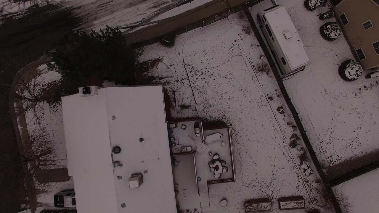 Overhead snowy residential block with a white roof and road