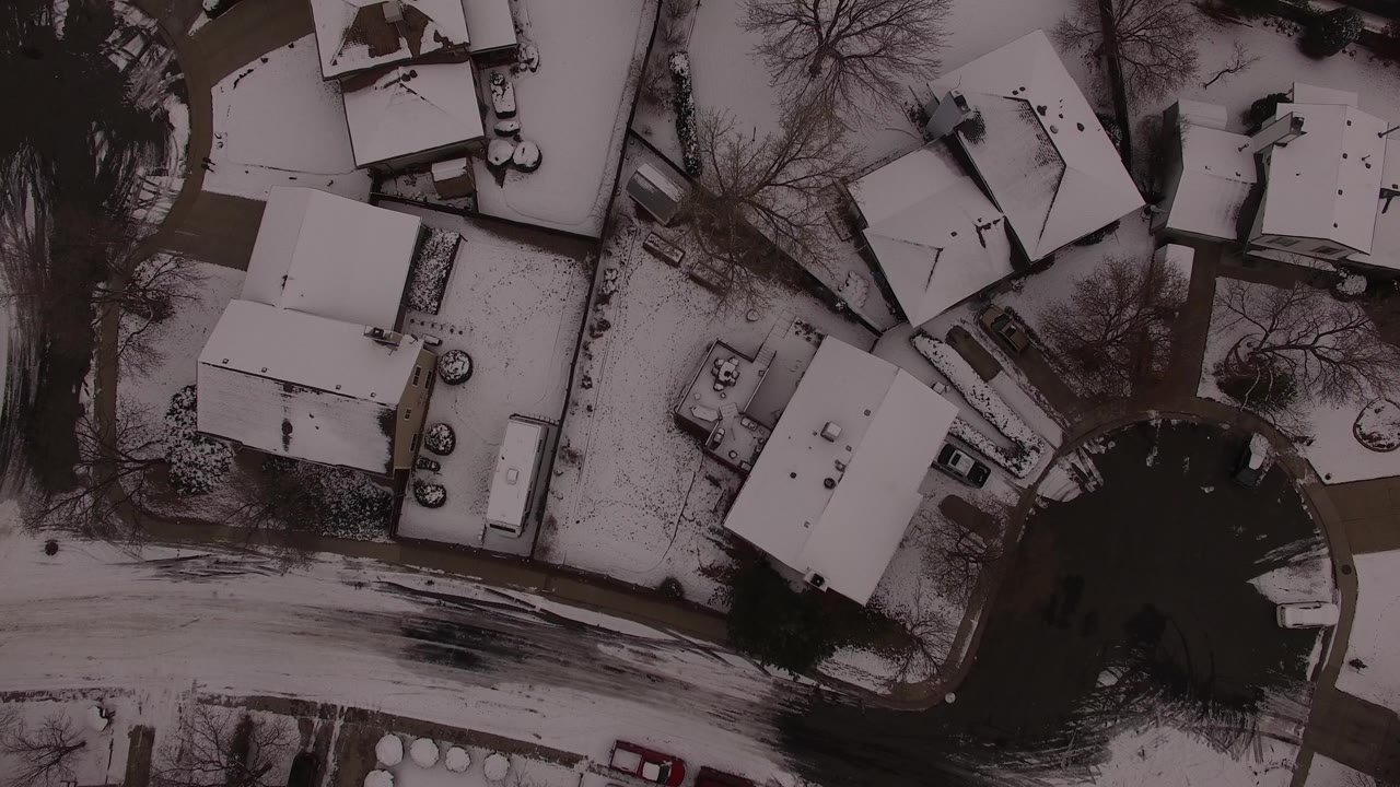 Aerial view of snow-covered homes and neighborhood road.