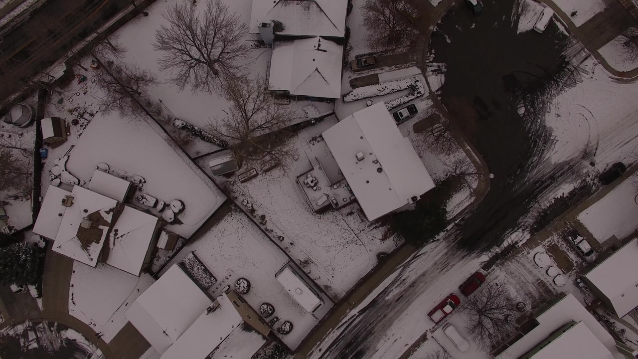 Aerial view of snowy houses beside a dark winter road.