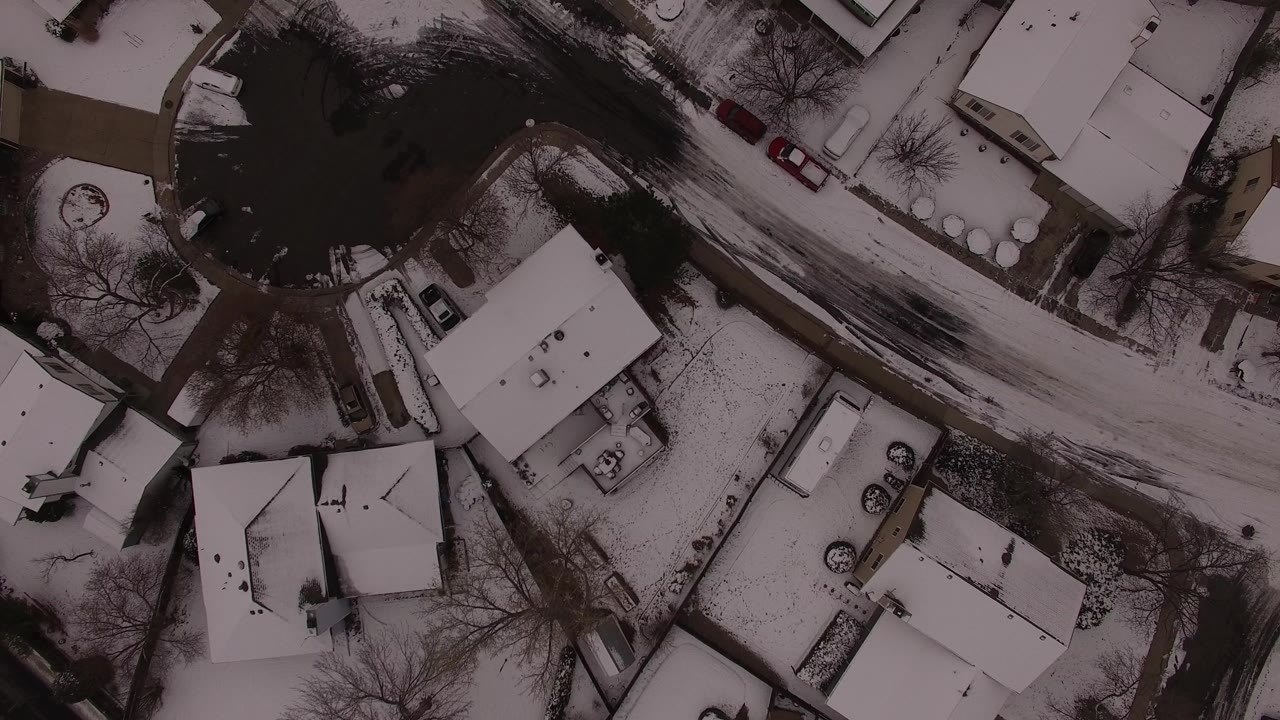 Overhead view of snow-covered homes and a winding street.