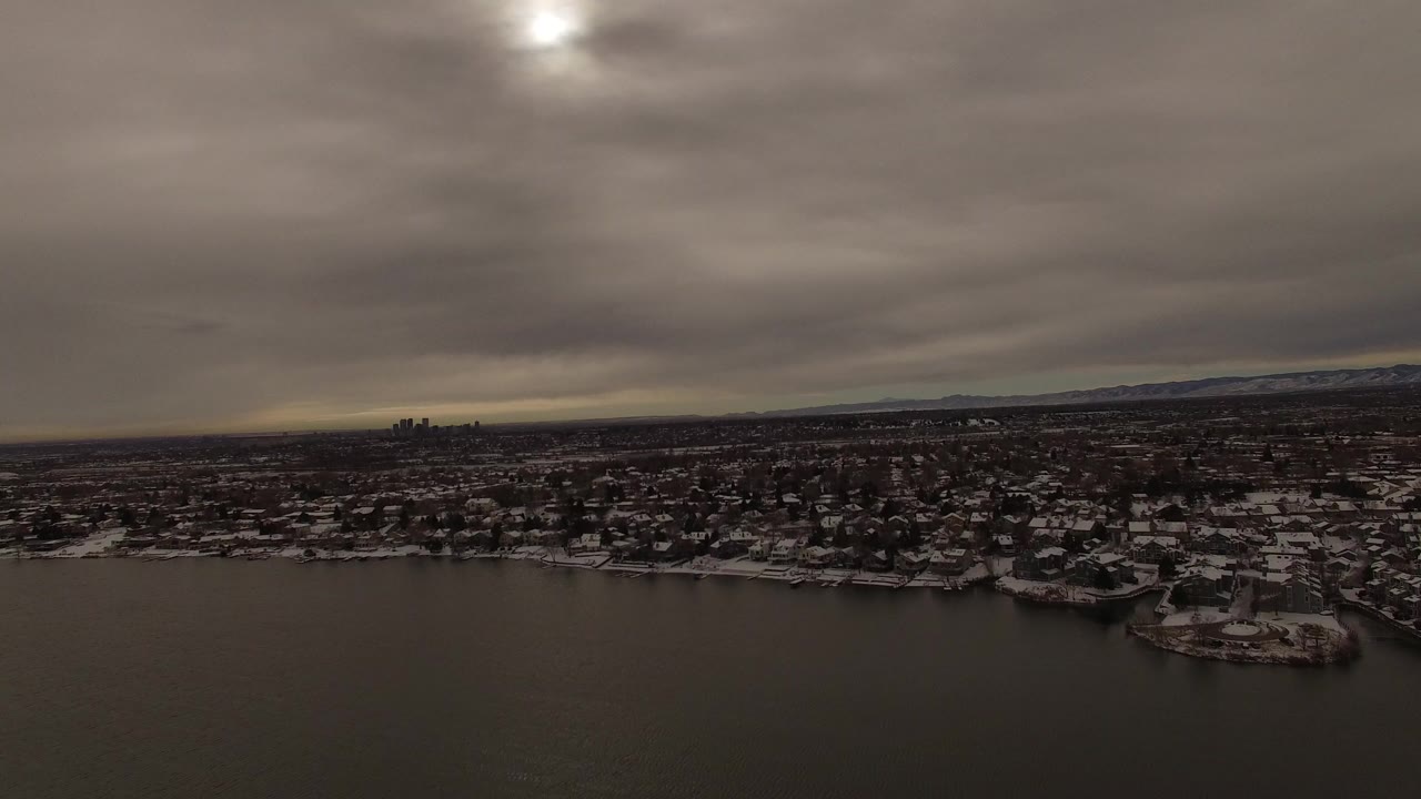 Wide winter lake view with snowy homes and heavy clouds