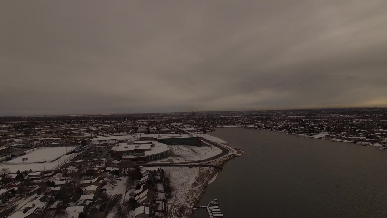 Snowy lakeside city viewed from above under gray clouds