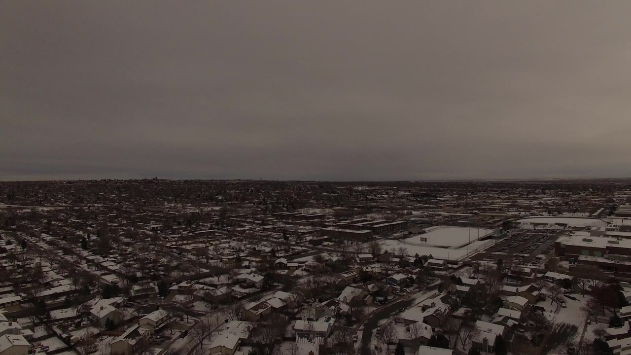 Snow-covered suburban neighborhood under a gray winter sky.