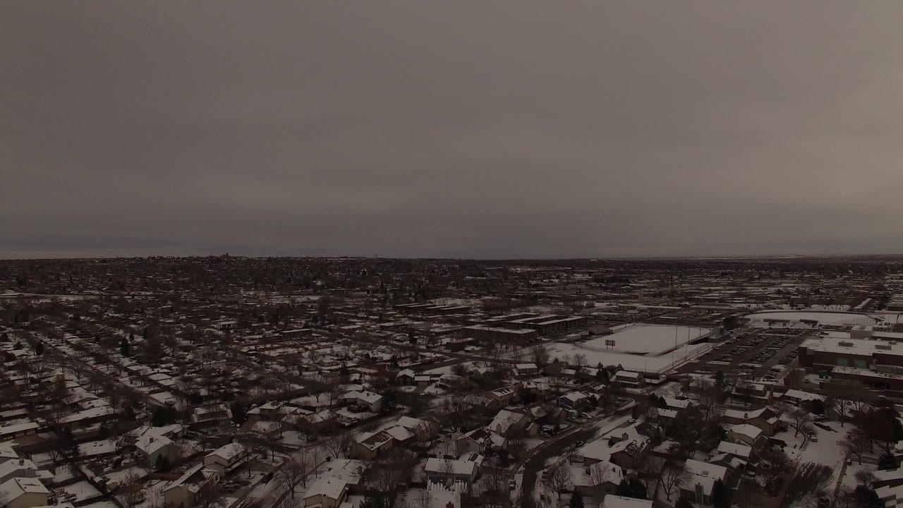 Jefferson County, Colorado appears from above with snow on rooftops, bare trees, low buildings in the midground, and no visible people.