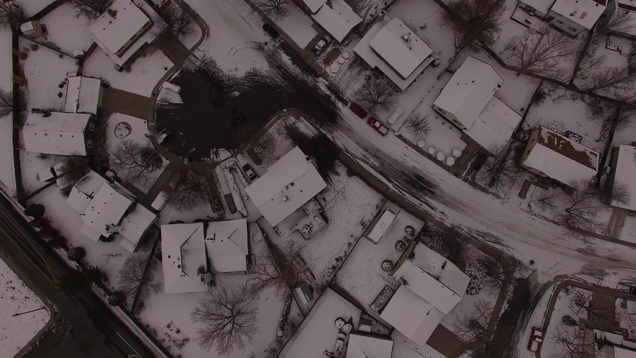 Overhead snowy residential neighborhood with roads and houses
